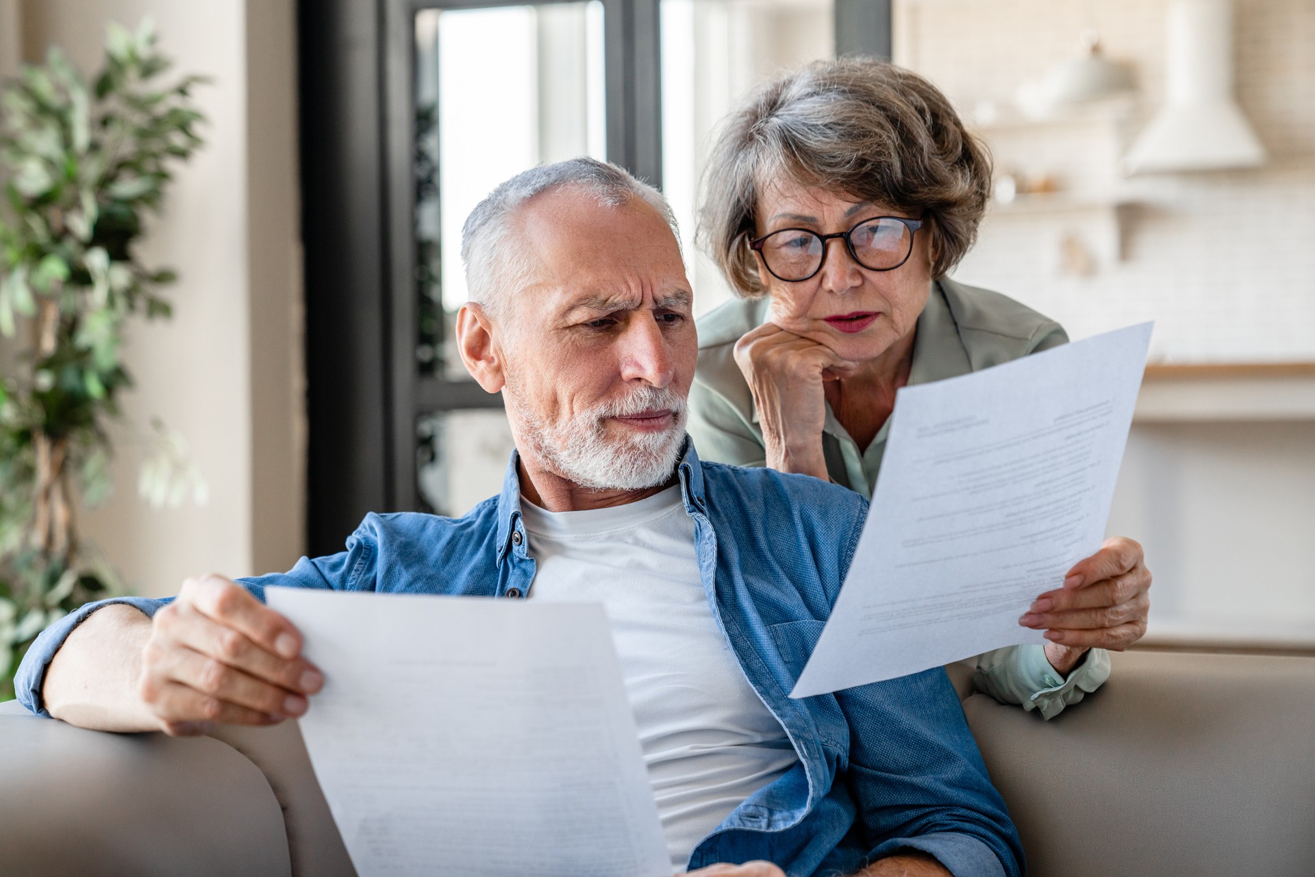 Grands-parents âgés lisant des documents, ayant des problèmes de dette avec perte d’argent